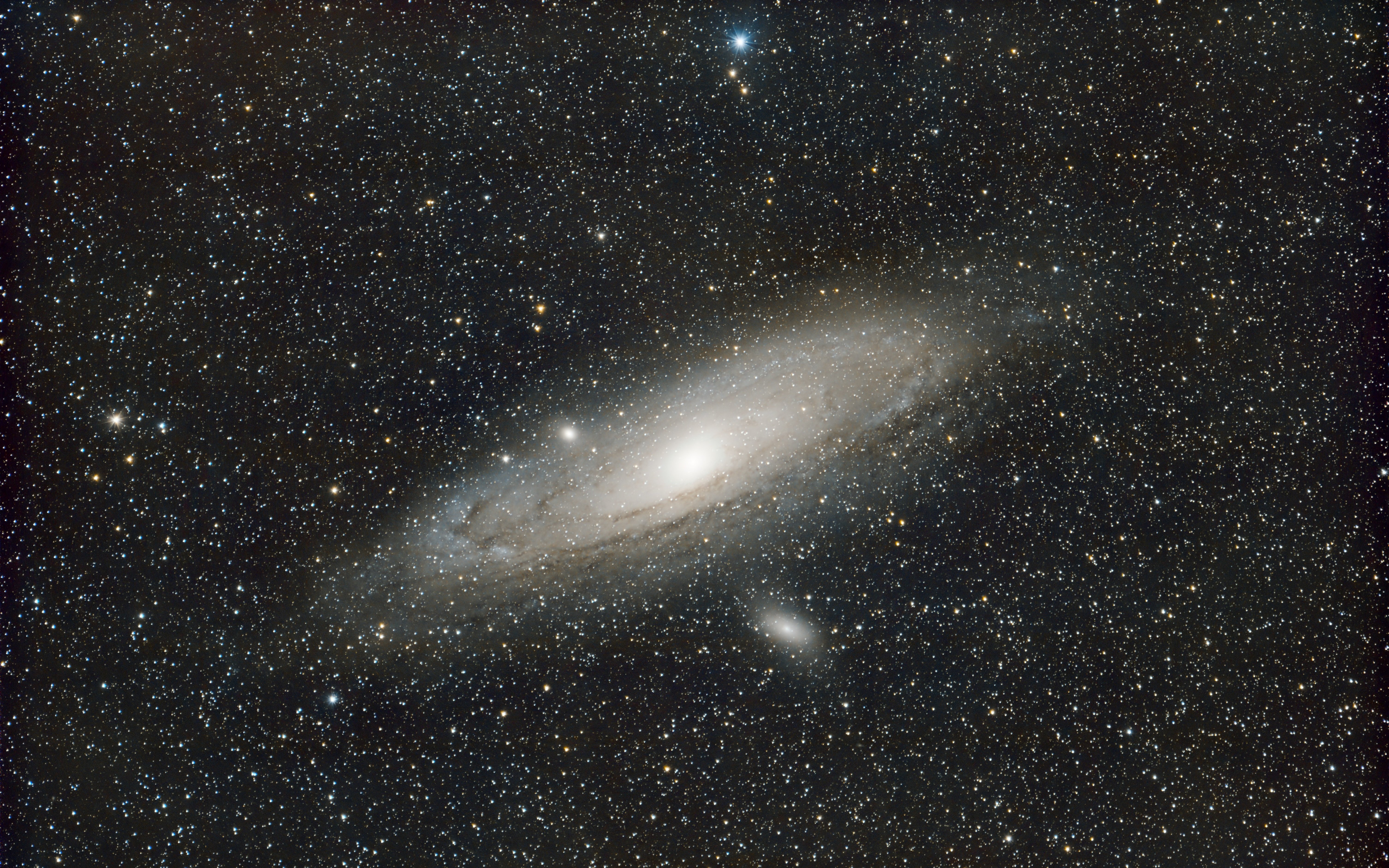 Une galaxie spirale lumineuse, inclinée dans un ciel noir rempli de milliers d’étoiles.